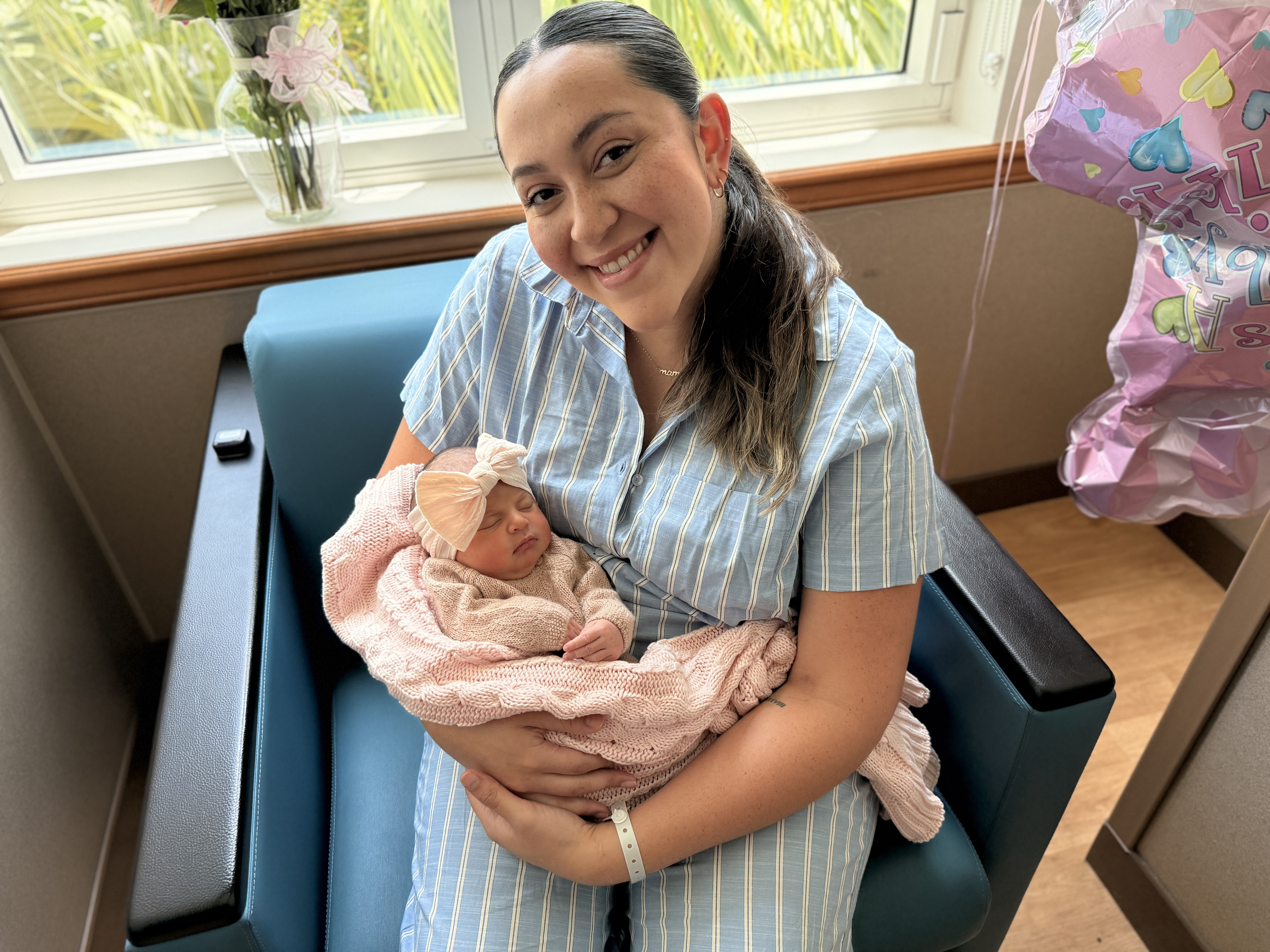 A newborn in a pink blanket, held with care